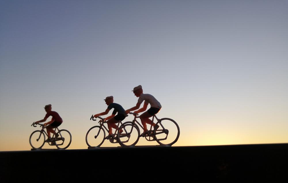 Petits cyclises en plastique faisant la course dans le soleil couchant