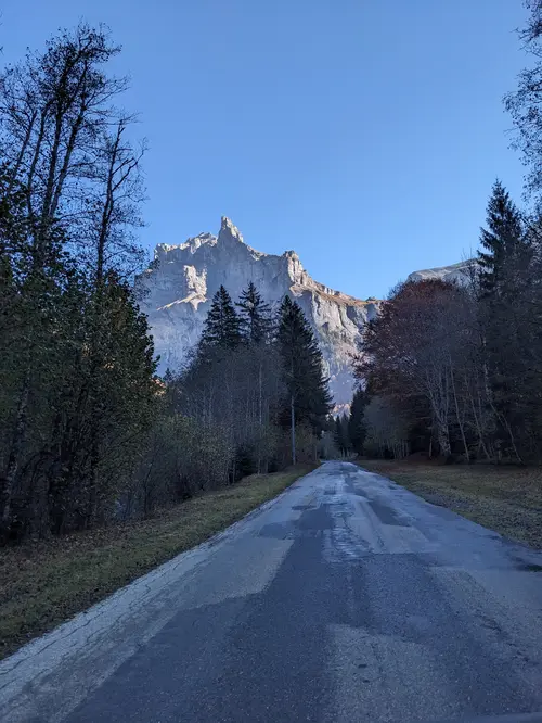 approche sur la route menant au Cirque des Fonds à Sixt-fer-A-Cheval en Haute-Savoie, France. Petite route droite dans la forêt aux couleurs d'automne avec la montagne culminante à 3000 mètres