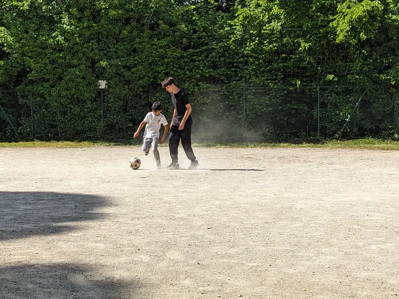 2 enfants jouent au football sur un terrain de street