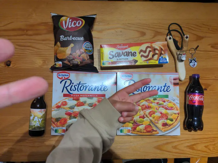 Vue de haut des achats pour le repas de réveillon, pizza, bière, coca, chips et gâteau Savane